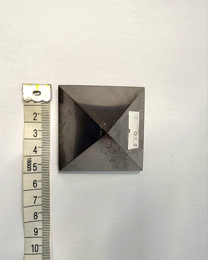 A polished black shungite crystal pyramid providing protection on your spiritual journey.