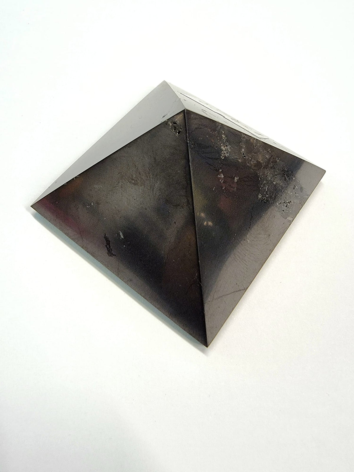 A polished black shungite crystal pyramid providing protection on your spiritual journey.