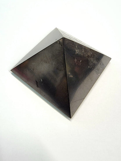 A polished black shungite crystal pyramid providing protection on your spiritual journey.