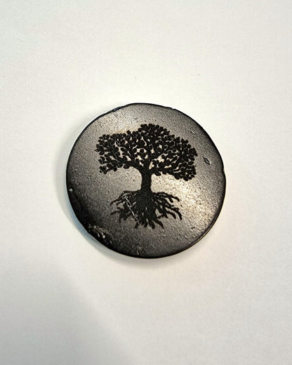 A sticker made from black shungite with a Tree of Life symbol etched into it.  Used to attach to electronic devices to absorb EMF.